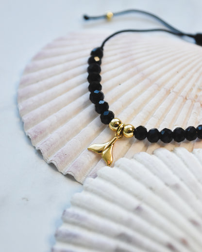 Pulsera Ajustable con Cristales Negros y Dije Colita de Ballena en Baño de Oro